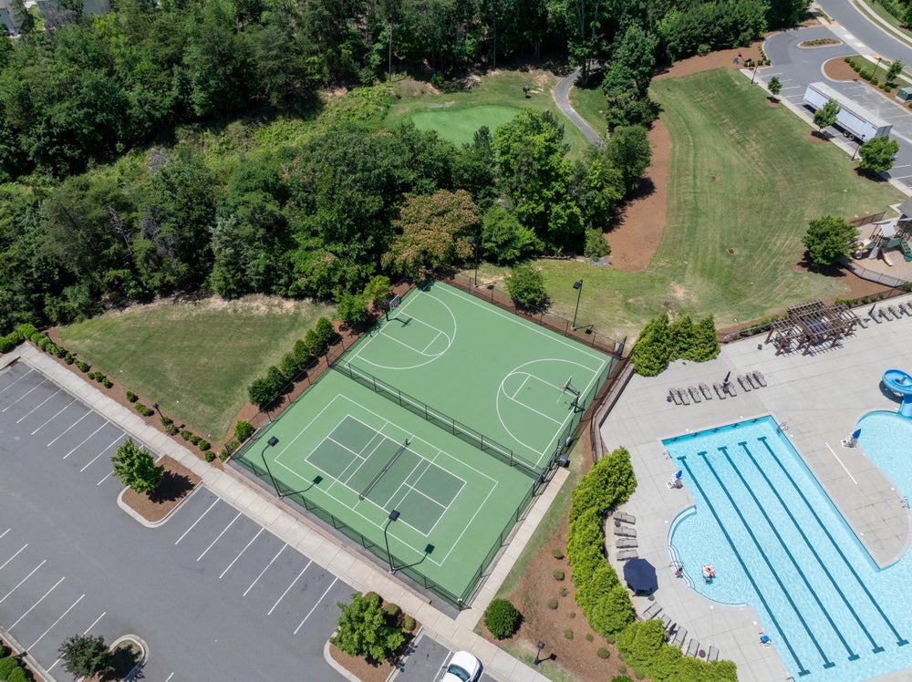 Aerial view of community amenities with tennis courts, basketball court, swimming pool, and open lawn areas