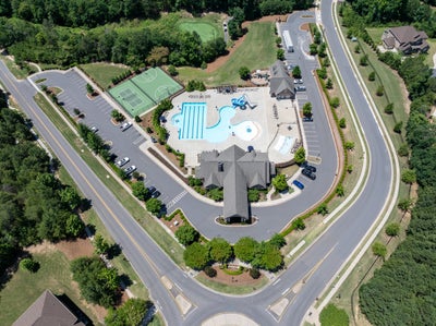 Aerial view of residential community amenity center with pool, tennis courts, and clubhouse