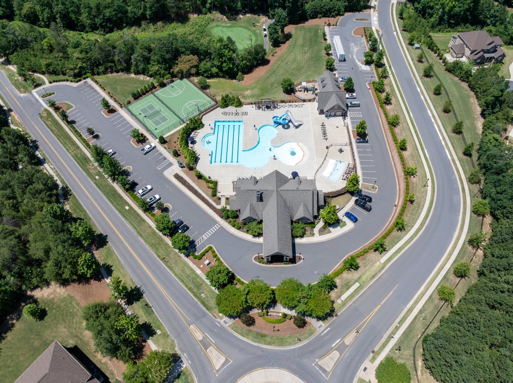 Aerial view of residential community amenity center with pool, tennis courts, and clubhouse
