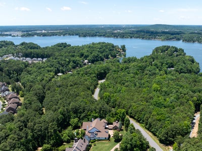 Aerial view of lakefront residential community with wooded lots and waterfront access