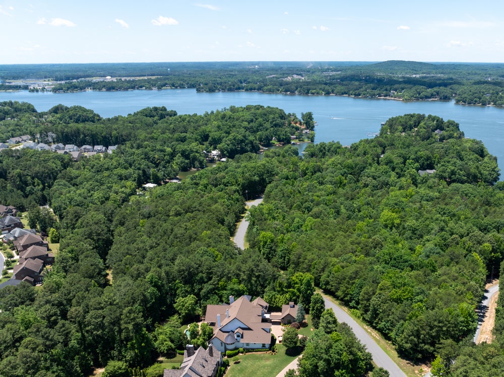 Aerial view of lakefront residential community with wooded lots and waterfront access