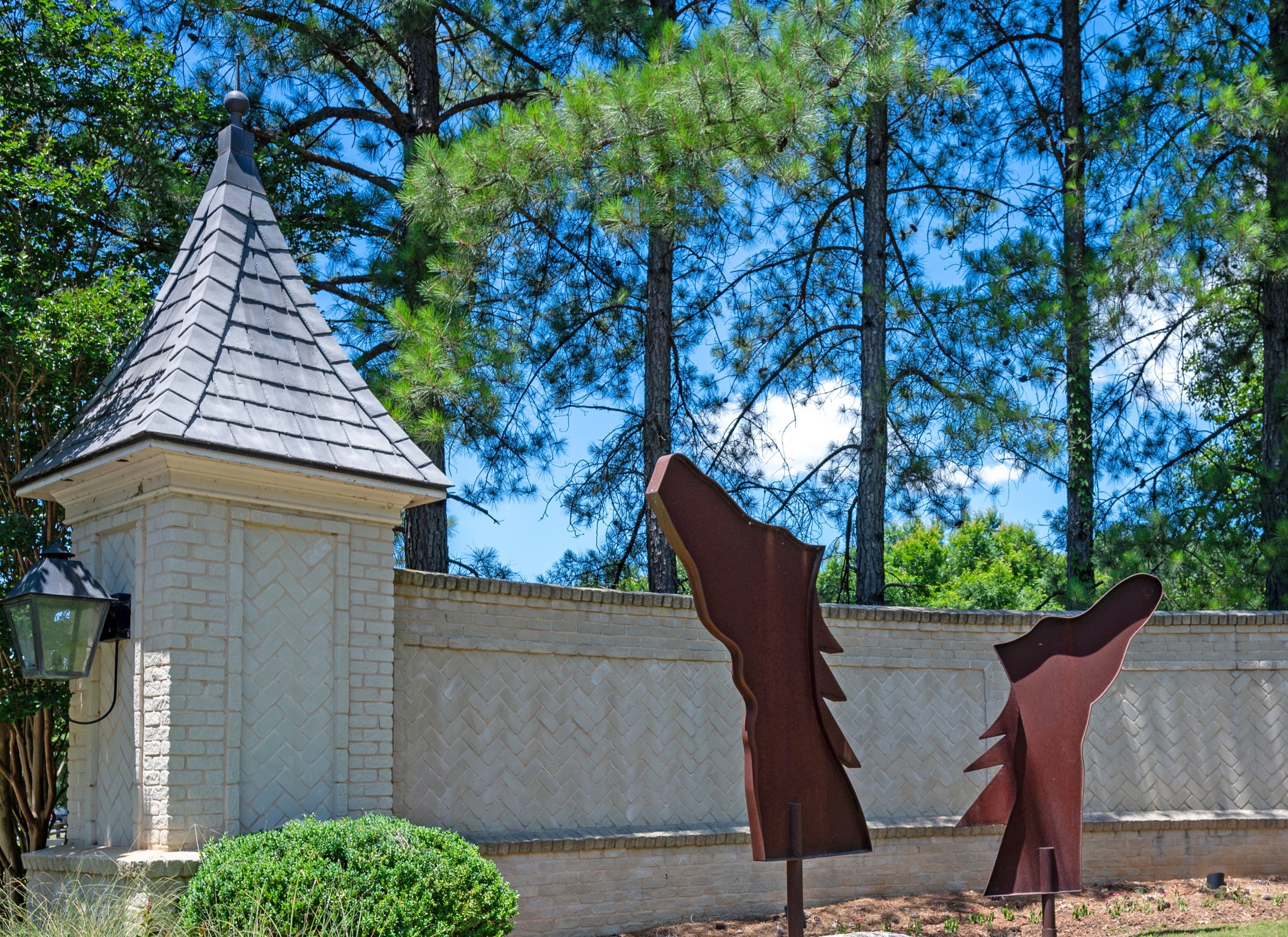 Brick entrance with decorative tower and metal art sculptures near patterned wall
