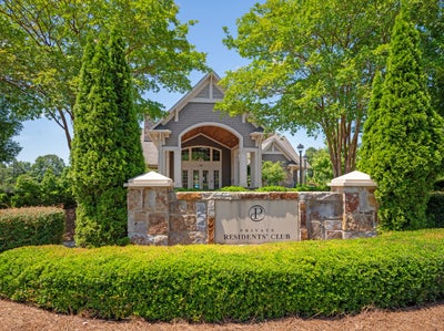 Private residents' club entrance with stone sign and clubhouse building surrounded by mature trees