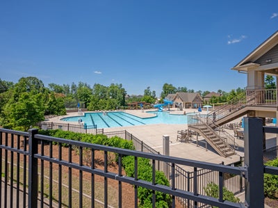 Community pool with lap lanes, water slide, and clubhouse surrounded by trees