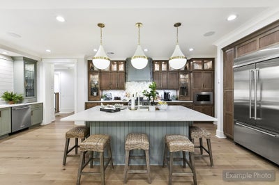 Open kitchen with large island, brown cabinets, white countertops, pendant lights, and stainless steel appliances