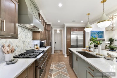 Modern kitchen with brown cabinets, white countertops, herringbone backsplash, and center island with pendant lights