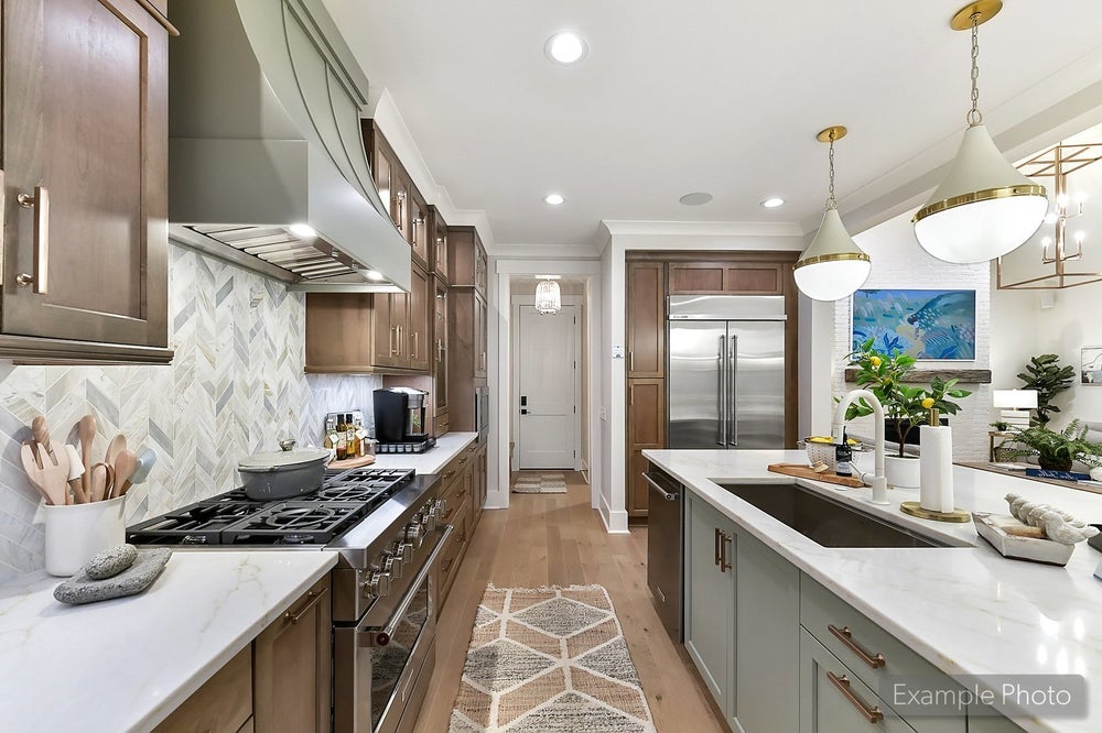 Modern kitchen with brown cabinets, white countertops, herringbone backsplash, and center island with pendant lights