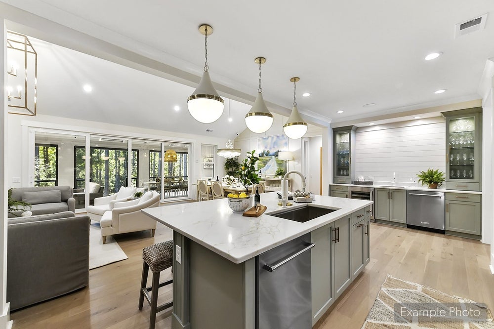 Open-concept kitchen and living room with gray island, white countertops, and pendant lighting