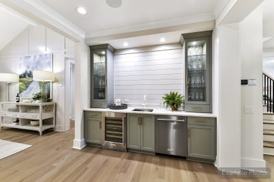 Wet bar with gray-green cabinets, glass display cases, wine cooler, and shiplap accent wall