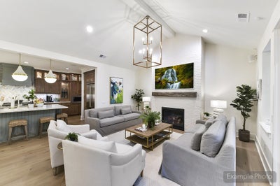 Open-concept living room with vaulted ceiling, fireplace, and view into kitchen