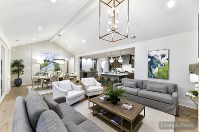 Open-concept living room, dining area, and kitchen with vaulted ceiling and modern furnishings