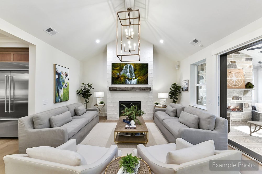 Modern living room with vaulted ceiling, white brick fireplace, and gray sectional sofas