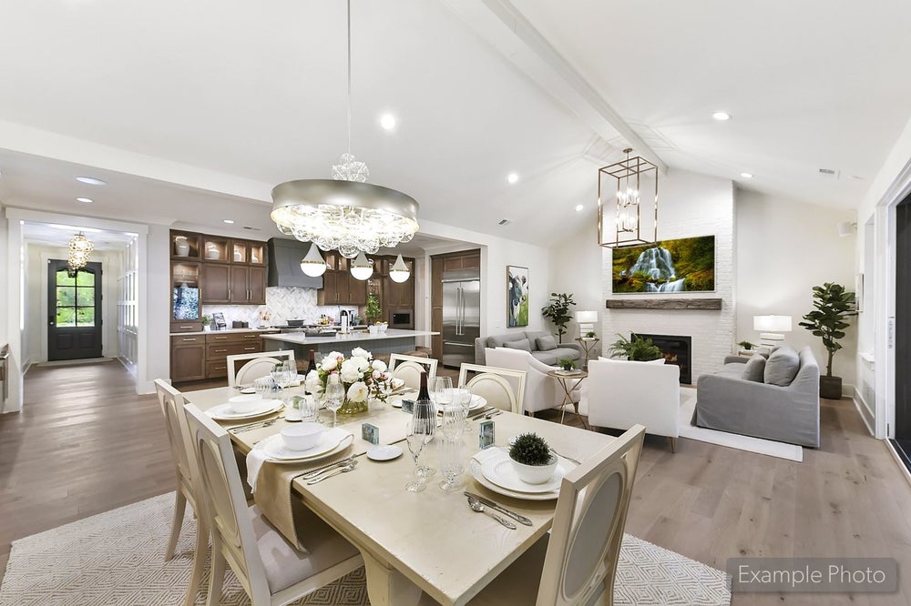 Open-concept living space with dining area, kitchen with dark cabinets, and living room with vaulted ceiling