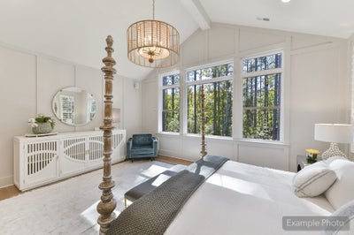 Master bedroom with vaulted ceiling, four-poster bed, and large windows overlooking trees