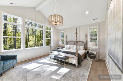 Master bedroom with vaulted ceiling, four-poster bed, and large windows overlooking trees