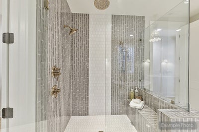 Walk-in shower with gray vertical tile, glass enclosure, and gold fixtures