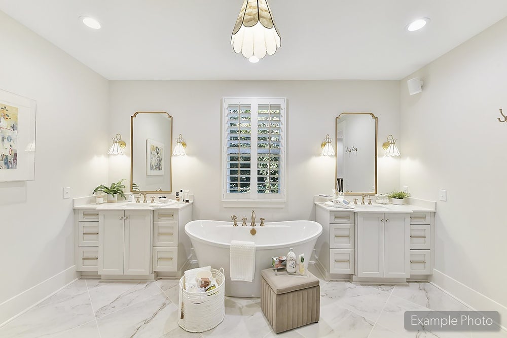 Master bathroom with freestanding tub, dual vanities, gold mirrors, and marble flooring