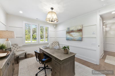 Home office with white shiplap walls, gray desk, and plantation shutters