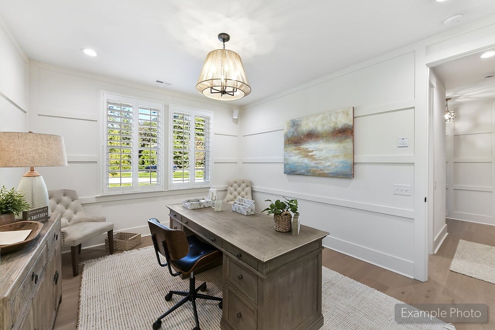 Home office with white shiplap walls, gray desk, and plantation shutters