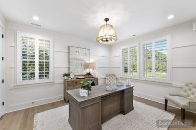 Home office with white shiplap walls, wooden desk, plantation shutters, and pendant lighting