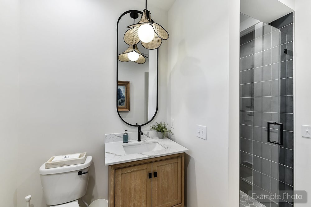 Modern bathroom with wood vanity, marble countertop, oval mirror, and decorative pendant light