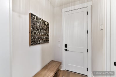 Entryway with white door, wooden bench, and decorative wall art with typography