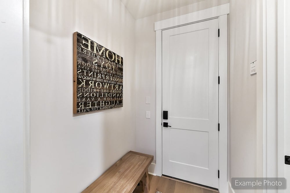 Entryway with white door, wooden bench, and decorative wall art with typography