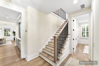 Two-story foyer with wooden staircase, black metal railings, and light hardwood floors