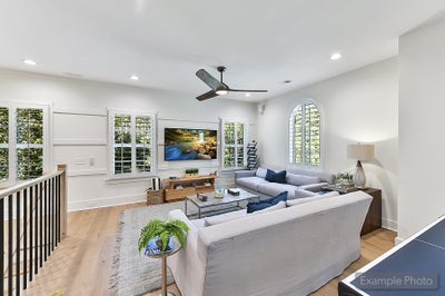 Bright living room with vaulted ceiling, white walls, hardwood floors, and sectional sofa