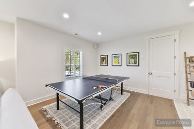Recreation room with ping pong table, hardwood floors, and framed wall art