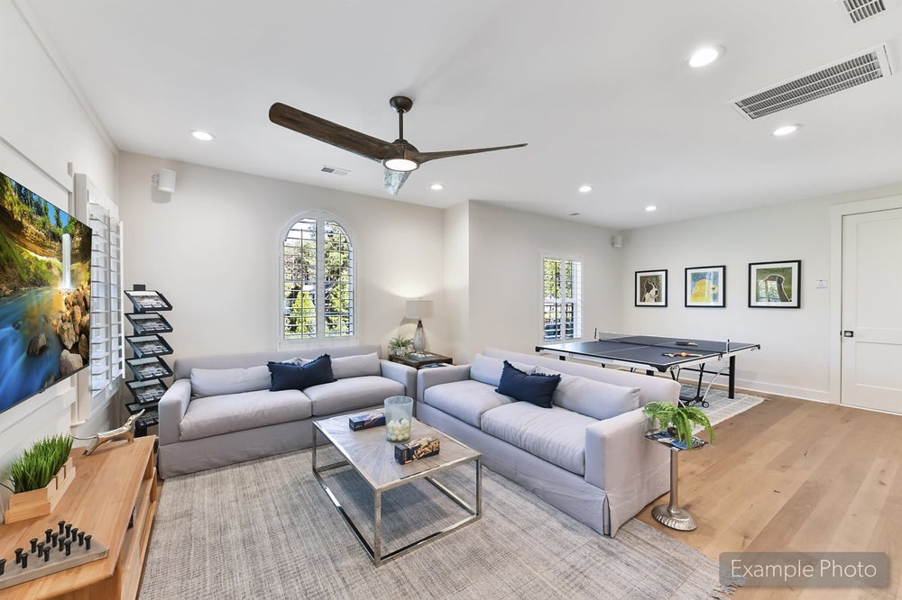 Recreation room with gray sofas, ping pong table, and ceiling fan