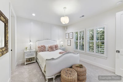 Bedroom with white paneled walls, plantation shutters, and upholstered bed frame