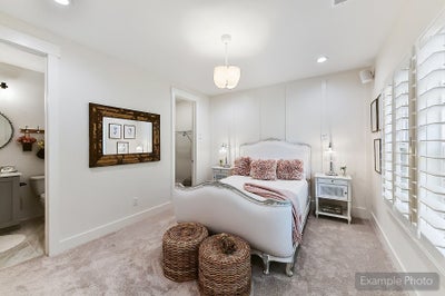 Bedroom with white upholstered bed, ensuite bathroom, and plantation shutters