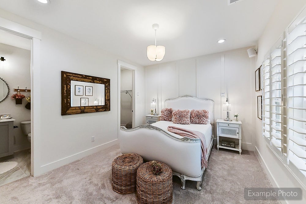 Bedroom with white upholstered bed, ensuite bathroom, and plantation shutters