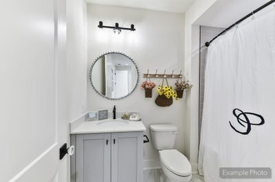 Bathroom with gray vanity, round mirror, white shower curtain, and decorative wall hooks
