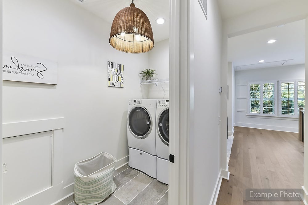 Laundry room with white cabinets, front-load washer and dryer, and wicker pendant light