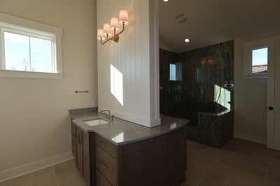 Modern bathroom with dark wood vanity, marble countertop, and glass-enclosed shower with green tile.