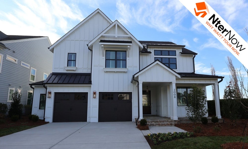 Two-story white house with dark garage doors and covered front porch entrance.