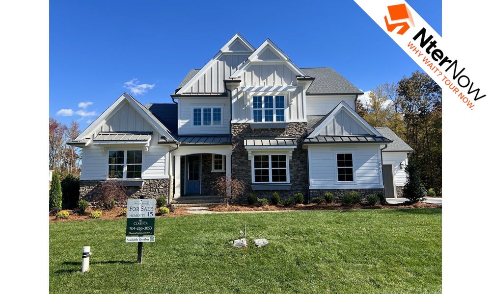 Large two-story white house with stone accents and a "For Sale" sign on the front lawn.
