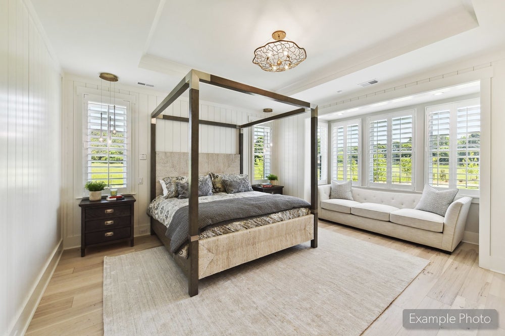 Master bedroom with four-poster canopy bed, white shiplap walls, and window seat with plantation shutters