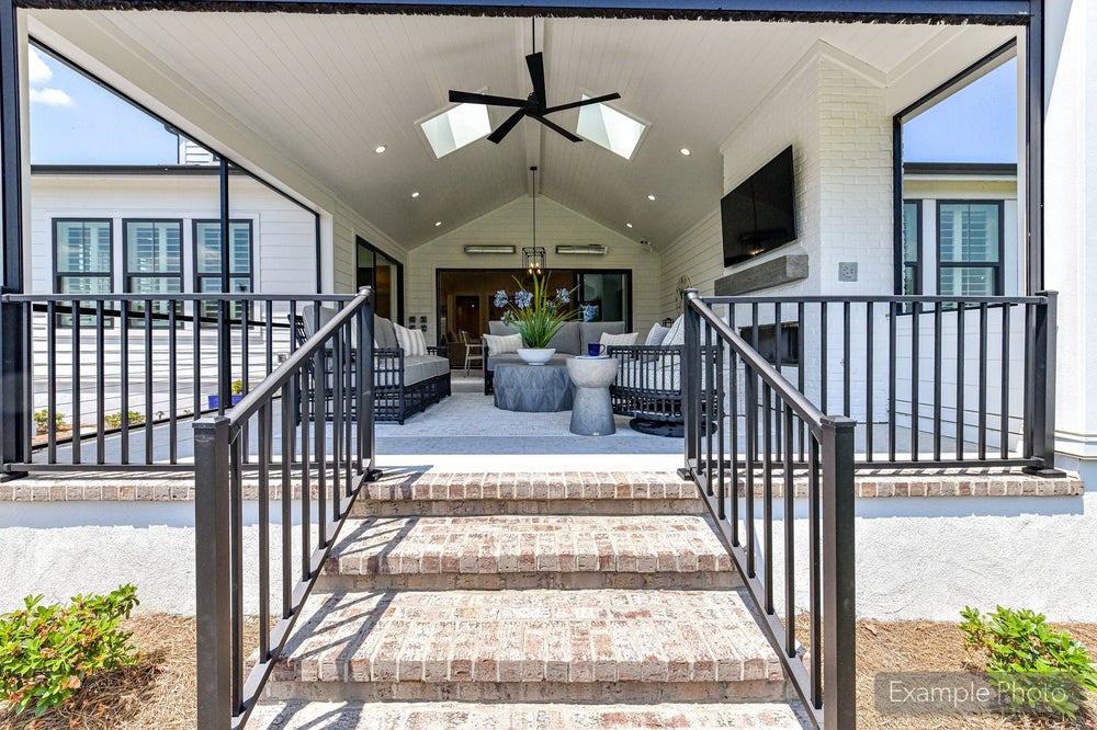 Covered outdoor patio with vaulted ceiling, ceiling fan, brick steps, and outdoor seating area with wall-mounted TV