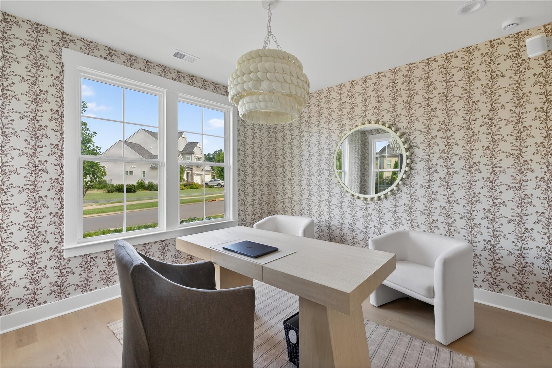 Home office with floral wallpaper, white desk, modern chairs, and pendant light fixture