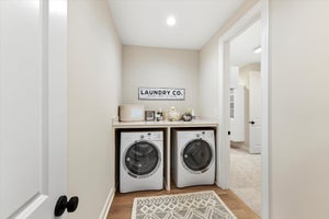 Laundry room with front-load washer and dryer under wood countertop with vaulted ceiling