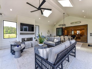 Covered outdoor patio with vaulted ceiling, fireplace, ceiling fan, and wicker furniture
