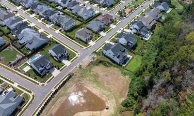Aerial view of suburban neighborhood with two-story homes and retention pond