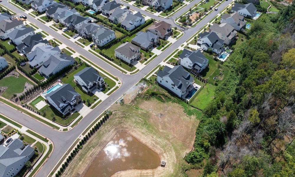 Aerial view of suburban neighborhood with two-story homes and retention pond