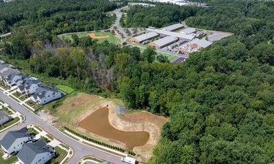 Aerial view of school campus with baseball field and residential neighborhood near retention pond