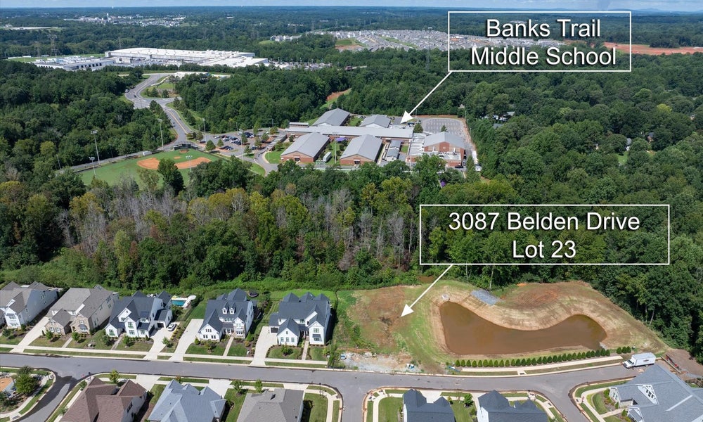 Aerial view of vacant residential lot near Banks Trail Middle School with nearby homes and wooded areas