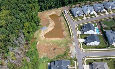 Aerial view of new residential subdivision with retention pond and modern homes
