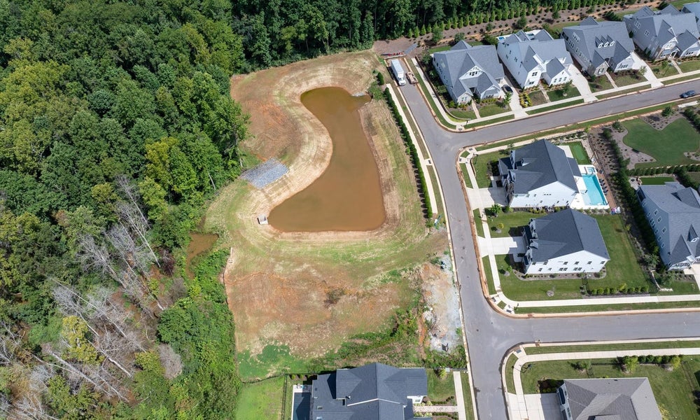 Aerial view of new residential subdivision with retention pond and modern homes